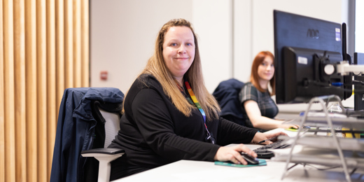 A person sat at a desk smiling towards the camera
