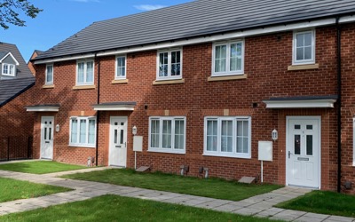 Red brick terraced houses with white windows and doors and a small front garden.