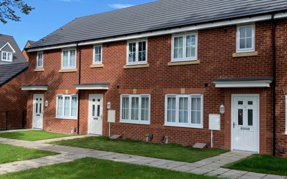 Red brick terraced houses with white windows and doors and a small front garden.