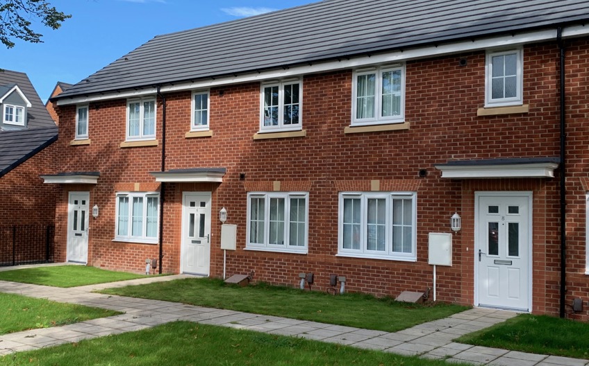 Red brick terraced houses with white windows and doors and a small front garden.