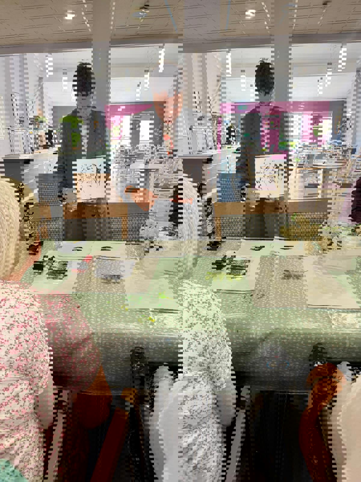 Person holding up a sheet with leaf prints during an arts and crafts session at a community space.